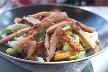 Grilled chicken and fresh vegetable salad on table.