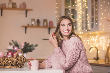 Cute blonde girl in tenderness pink pygamas at christmas decorated kitchen