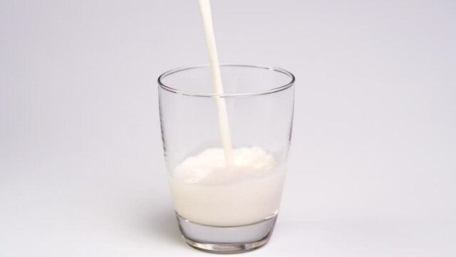 Pouring milk into the glass on white background.