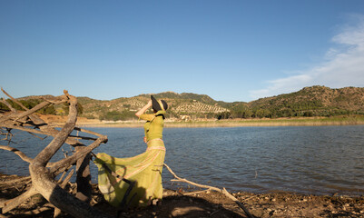 Mujer con vestido verde y pamela frente a un lago en Andalucía