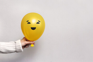 A man holds a balloon with a happy face in his hand. Joy, smiles, optimism in a person's life