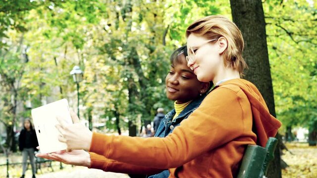Young, beautiful girlfriends taking taking selfie photo with tablet in autumn park, 4K
