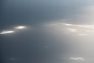 vue aérienne sur la surface bleue grise de la mer tachetée d'îlots de lumière provenant de rayons de soleil traversant les nuages 