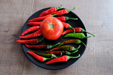 Red vegetables on a black plate. Organic tomatoes with peppers on wooden background. Summer or autumn concept. Natural food. It is called 