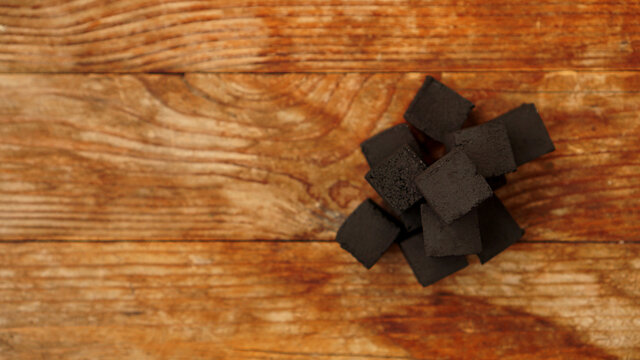 Cubes of coconut coal for hookah on wooden background. Place for text