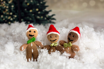 Three handmade knitted gingerman toys in a artificial snow