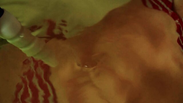 Medical procedure hydromassage in the bath. Female hand with a hydromassage, a slender girl in a bikin in the water in the bath.