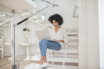 Fototapeta na wymiar Woman working on laptop while sitting on steps