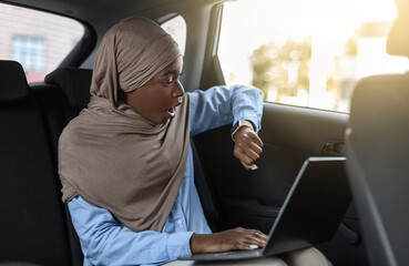 Being Late. Stressed Black Muslim Businesswoman Sitting In Taxi And Checking Time