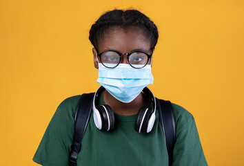 African Student Wearing Protective Face Mask On Yellow Studio Background