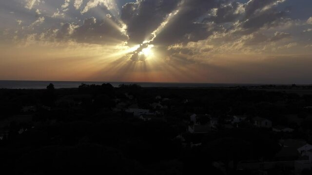 Dramatic sky with lightbeams over the town of Zahora with Atlantic Ocean beneath. Aerial view