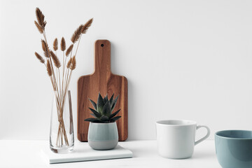 A mug, a potted houseplant, a clear vase and a wooden cutting board. Eco-friendly materials in the decor of the room, minimalism. Copy space, mock up