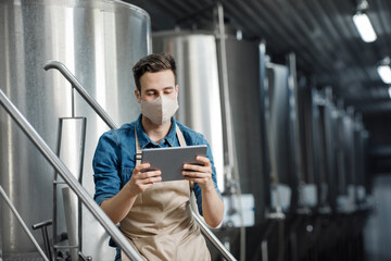 Brewery, modern gadgets and new normal. Millennial male worker holds tablet