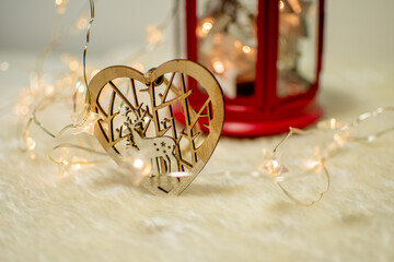 Festive christmas decorative handmade wooden heart with reindeer and lightning stars and red candlestick in the background