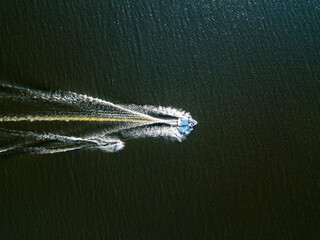 Naklejka premium Aerial drone view. Wake surfing behind a boat on the river on a sunny summer day.