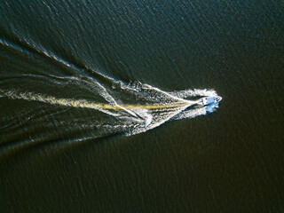 Aerial drone view. Wake surfing behind a boat on the river on a sunny summer day.