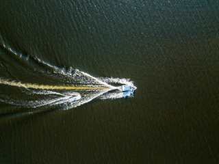 Aerial drone view. Wake surfing behind a boat on the river on a sunny summer day.