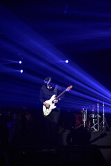 A musician man playing the Guitar on the stage with beautiful blue lighting