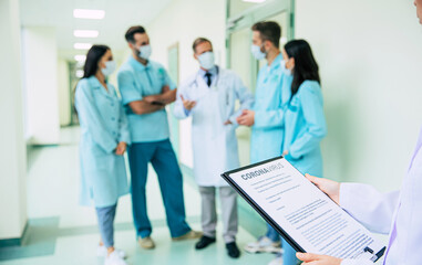 Fototapeta premium Close photo of doctor hands with coronavirus information blank on medical team background in the hospital