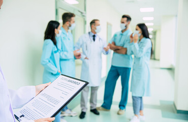 Close photo of doctor hands with coronavirus information blank on medical team background in the hospital