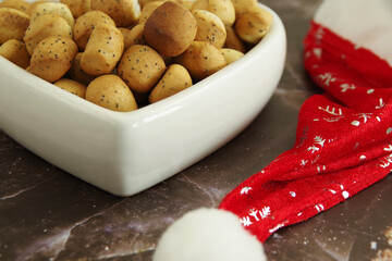 Christmas Eve cookies Kuciukai and Santa Claus red hat on brown background. Kuciukai are served during Christmas Eve dinner in Lithuania. Kuciukai are eaten with poppy milk.	
