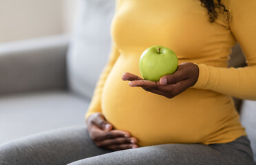 Cropped of black pregnant woman holding green apple