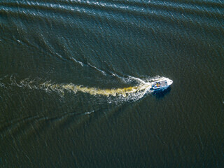 Naklejka premium Aerial drone view. The motor boat is sailing along the river. Sunny summer day, small waves.