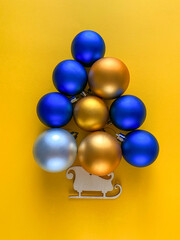 tree made of balls blue and gold on a yellow background, christmas background