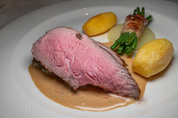 Grilled steak with vegetables on white plate with sauce.