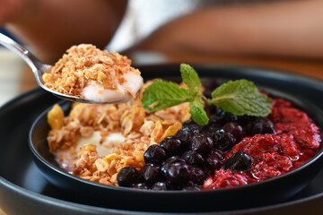Ready to eat, Yogurt with Granola in a stainless steel spoon.