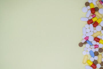 A lot of colorful tablets and pills on the right. Yellow background, copy space