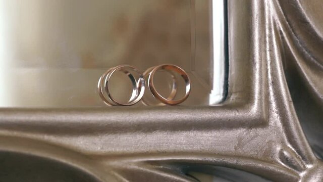Close-up of gold wedding rings on an antique mirror. Wedding chores. Day of the solemn wedding. Accessories of a couple of lovers. Wedding luxury, selective focus, shallow depth of field