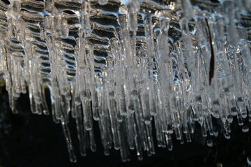 Close up of icicles of frozen water in freezing Winter weather hexagon metal wire covering garden...