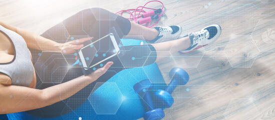 Fitness at home, remote training with virtual instructor. Woman in sportswear sitting on the floor with dumbbells laptop at home. Sports and recreation concept in lockdown with fitness apps online