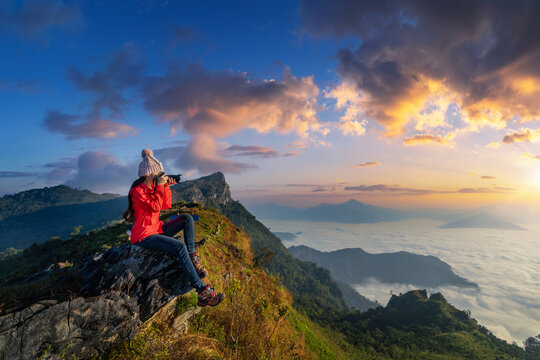 Traveller sitting on the rock and holding camera take photo at Doi pha mon mountains in Chiang rai, Thailand.