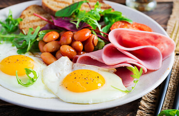 English breakfast - fried egg, beans, tomatoes, sausage,ham and toast.