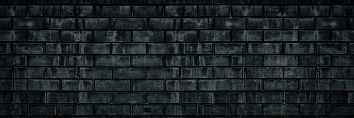 Black shabby old brick wall wide texture. Dark gray rough masonry. Gloomy grunge brickwork widescreen background