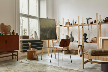 Unique artist workspace interior with stylish teak commode, wooden easel, bookcase, artworks,...