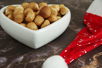 Christmas Eve cookies Kuciukai and Santa Claus red hat on brown background. Kuciukai are served during Christmas Eve dinner in Lithuania. Kuciukai are eaten with poppy milk.