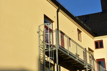 metal fire escape and  black gutter  and tiles  at yellow wall and red window frame with blue sky  at norway scandinavian europe. europe design