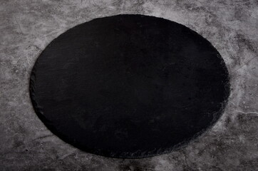 Empty black rustic slate stone plate on dark concrete background, copy space, top view