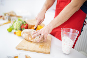 Male hands slicing bread on a cutting board