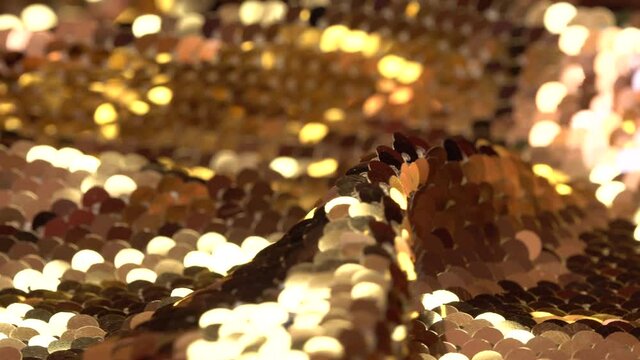 Gold sequin fabric. Christmas holiday abstract glitter background with blinking lights. Fashion luxury fabric glitter, spangles, paillettes