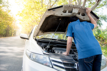 An Asian man opens the bonnet to check the engine compartment. Because his car is broken