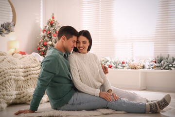 Happy couple sitting on floor at home. Christmas celebration