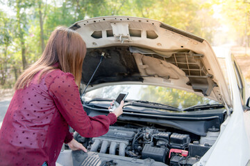 An Asian woman is calling for help because her car is broken and she is frustrated.