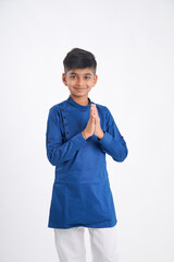 Cute indian little boy in namaste or praying pose over white background