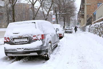 City after blizzard. Cars parked on a street covered with snow. Kyiv, Podil district, Ukraine