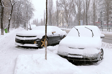 City after blizzard. Cars parked on a street covered with snow. Kyiv, Ukraine