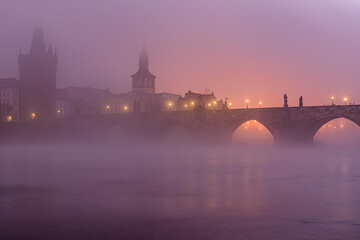 A mysterious autumn dawn at Charles Bridge covered in thick mist in historical center of Prague. 